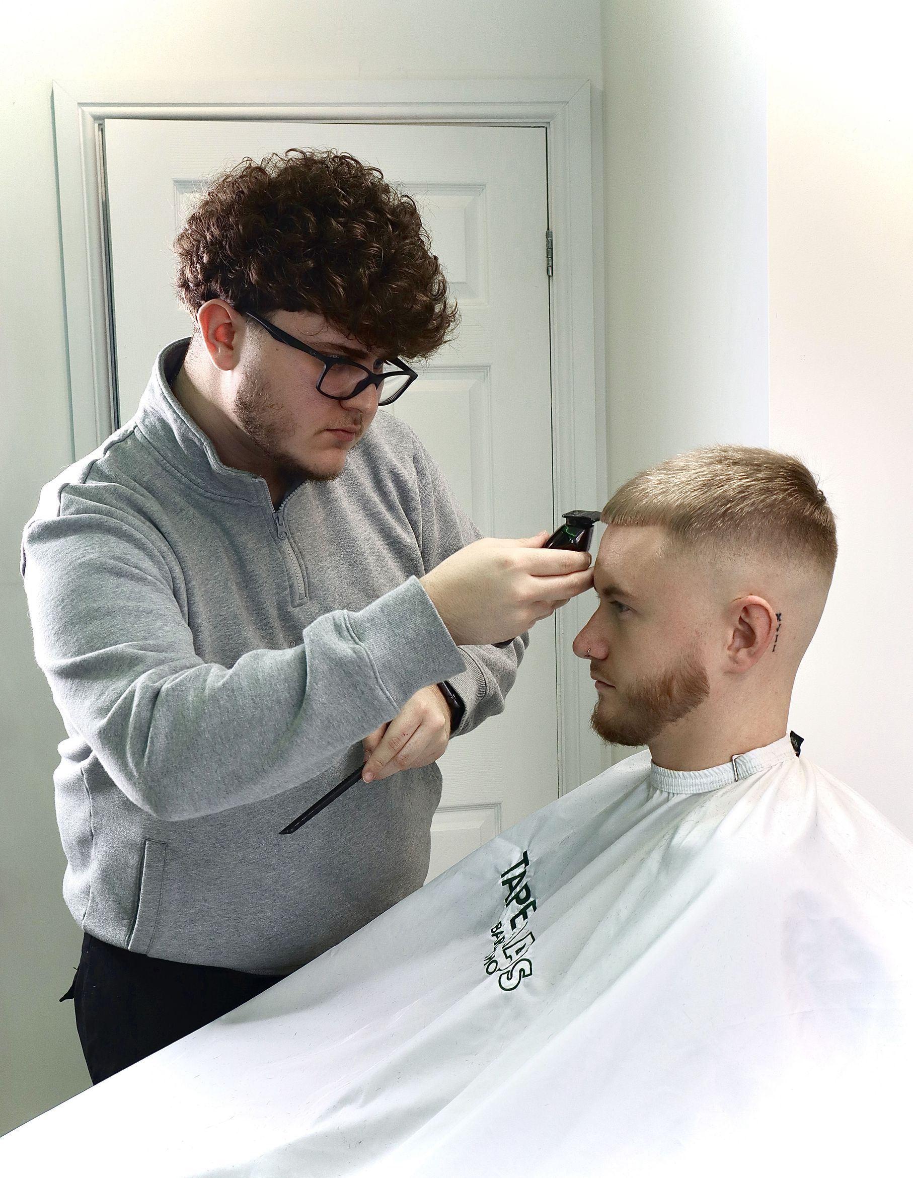 Riley cutting a client's hair with clipper